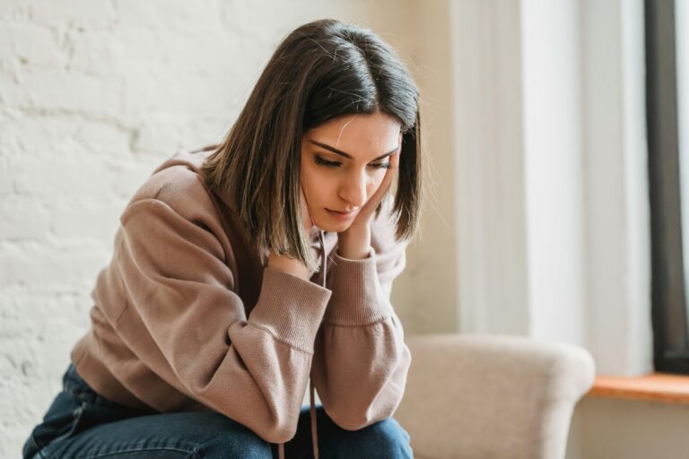 stressed young ethnic woman grabbing head while sitting on chair