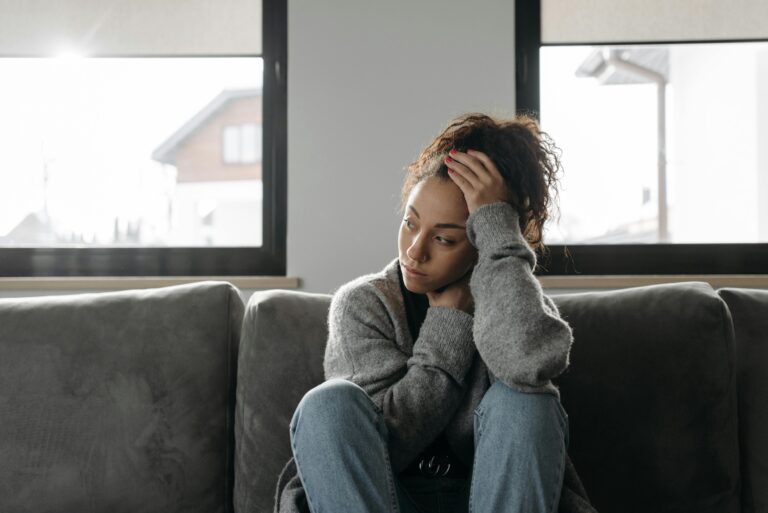 Woman sitting on couch, staring to one side.